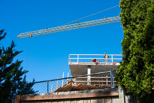 Construction worker high up on building project working on grouting structural post-tensioning wire strand holes running through concrete slab of floor
