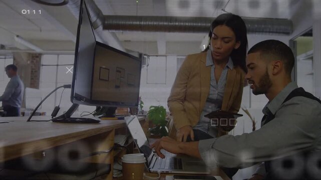 Seated man pointing laptop and woman leaning tab reviewing IT data while green HUD flickering