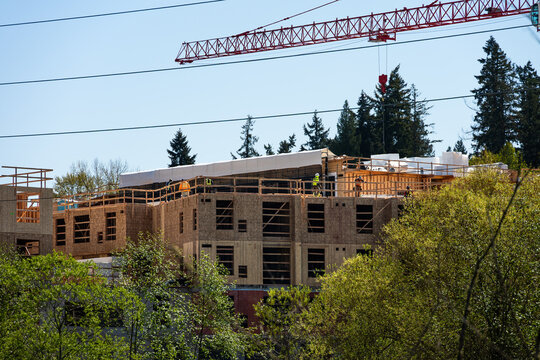 Major building commercial construction project, construction workers on top floor working on wood framing, multistory housing real estate development
