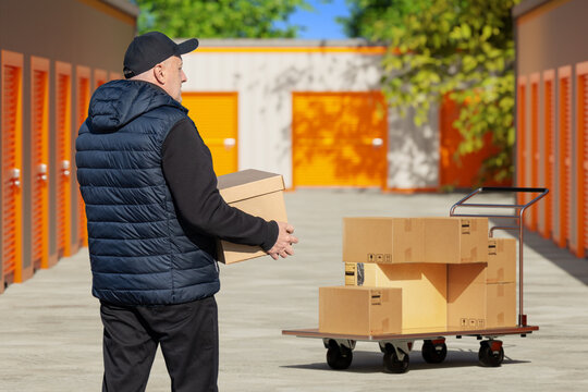 Man carries moving boxes at self storage facility, preparing relocation and personal storage service.