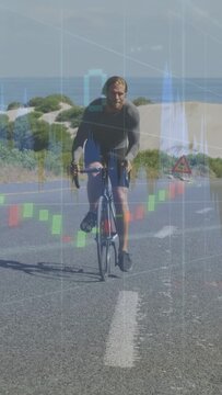 Vertical video: Cyclist riding toward camera on coastal road, raising trade charts overlaying bike