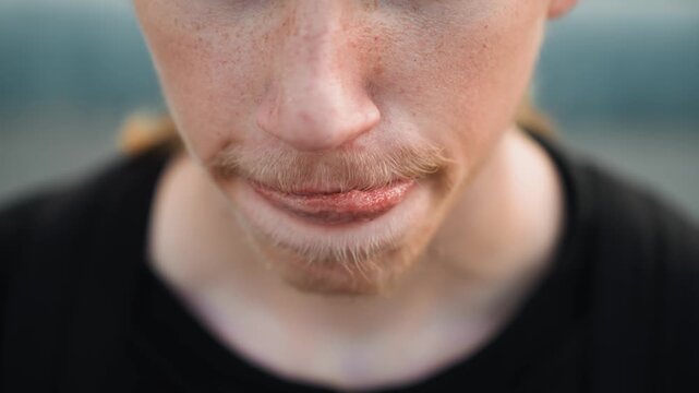 Frontal closeup white male shy smirk, subtle mouth movements, freckles and soft stubble, downcast gaze, introspective mood, street artist pausing between lines, vulnerable candid moment