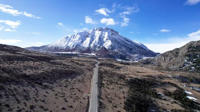 Drone view road leading to snow capped mountains in Baxoi County, Qamdo Prefecture, Tibet, China, high angle view of cars driving on asphalt road on Qinghai-Tibet Plateau, 4k real time travel footage.