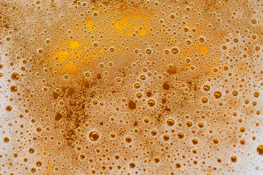 Golden beer bubbles macro texture with foam abstract background close up