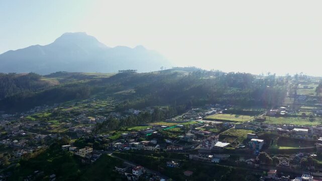 Otavalo, Ecuador: 5-1-2023: small farms are build on a hill surrounded by high mountains early in the moring during sunrise