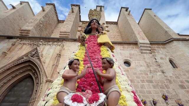 Valencian Fallas festival presenting the Virgin of the Forsaken sculpture, a traditional structure covered in an intricate dress of colorful fresh flowers during the Ofrenda de Flores in Gandia