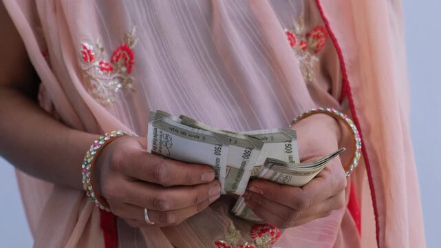 Close up of an Indian woman in traditional attire counting 500 rupee notes