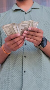 Close up of a man counting 500 rupee Indian currency notes outdoors