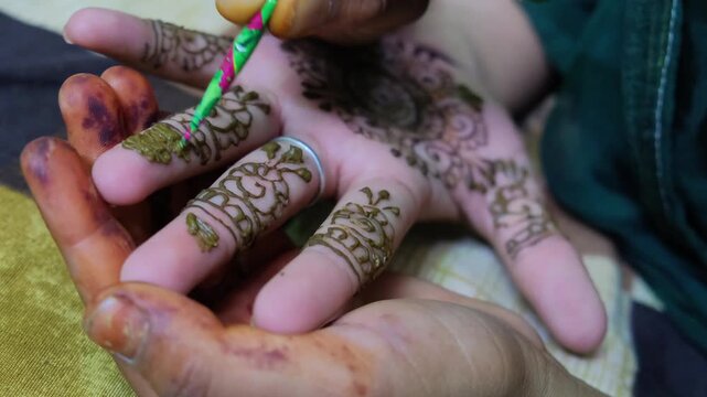 Macro shot of an artist applying detailed henna patterns on fingers using a cone