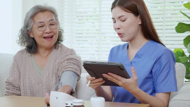 Asian woman nurse measuring blood pressure senior patient, medical checking for hypertension monitoring with digital tablet, caregiver support elderly woman with arterial blood pressure device.
