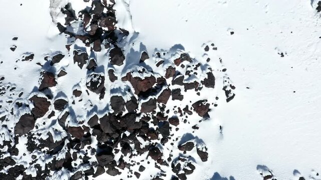 Aerial top view of in snow covered rocks on top of a mountain