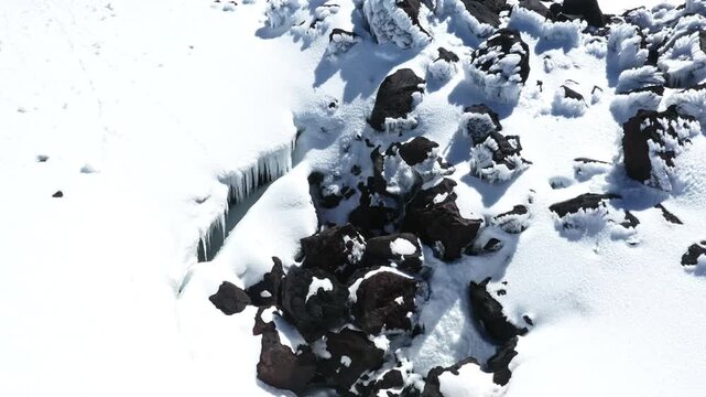 Moving over a spelonk and rocks covered in icicles, a beautiful winter background