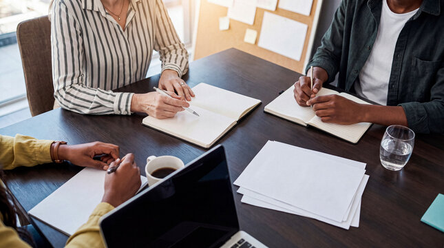 Diverse team members collaborating and writing notes during a productive business meeting at a modern office table.