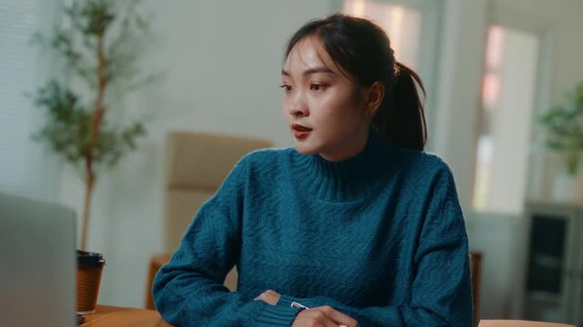 Focused asian female student taking notes and talking on a video conference call, studying online. Remote working and elearning concept