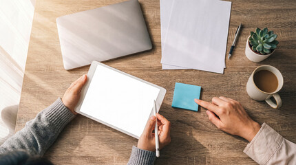 Obraz premium High-angle photograph of hands working efficiently on a modern digital tablet with a blank screen and stylus.