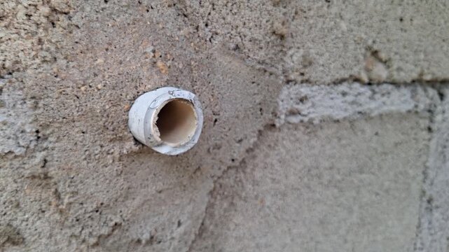 Close Up of Broken White PVC Pipe Inside Concrete Brick Wall, Damaged Water Plumbing System in Residential Building Construction