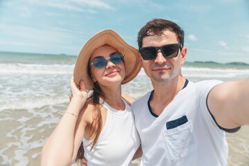 Obraz premium Couple taking selfie together at beach during summer vacation capturing romantic travel lifestyle moment with happiness connection and relaxed atmosphere