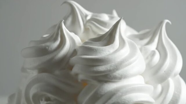 Close-up of a swirl of white, creamy dessert topping against a soft, neutral background, perfect for culinary and food-related projects