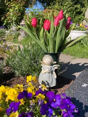 Obraz premium Tulpen, Blumen und Engel schmücken ein Grab auf dem Friedhof im Frühling 