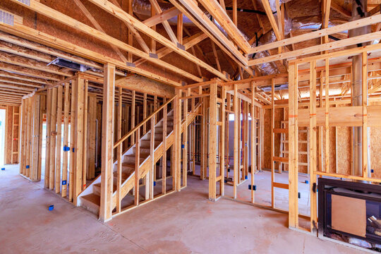Workers are framing walls beams installing staircase in anew home under construction in suburban location.