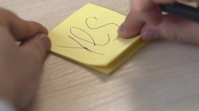 Hands Write Affirmatively. Focus On Hands Making Decisive Marks On Bright Yellow Paper In Workspace. Media