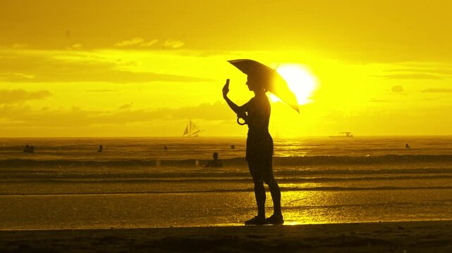 Silhouette of woman with umbrella in rain, epic golden sunset Boracay beach