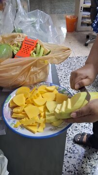 Vertical 4K close up of female hands chopping fresh mango