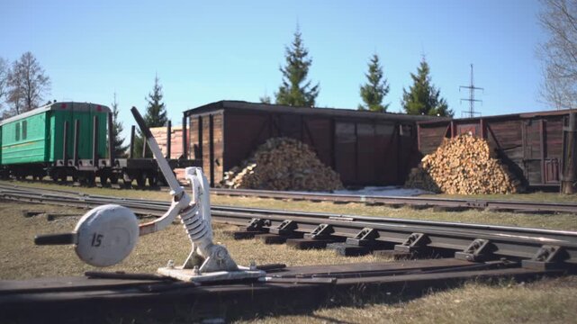 Rail Yard Landscape. Sunny Scene Showcasing Aged Rail Switch Surrounded By Cargo Cars And Natural Scenery. Media