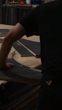 Focused Craftsman Meticulously Positions Complex Starshaped Inlay Within Round Plywood Panel In Workshop . Media