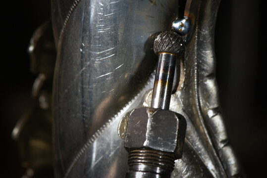 Electric straight grinder with carbide burr grinding steel surface on dark workshop close up background.