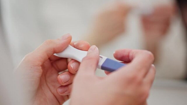 Close-up of hands holding a positive pregnancy test kit, representing pregnancy, motherhood, fertility, women&rsquo;s health, family planning, and medical testing at home.