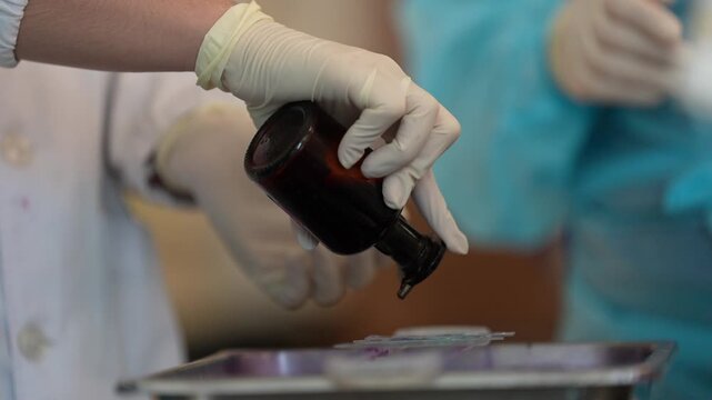 Staining slide laboratory hand glove applying dye to glass microscope specimen in medical clinic with scientific sample preparation and focused work