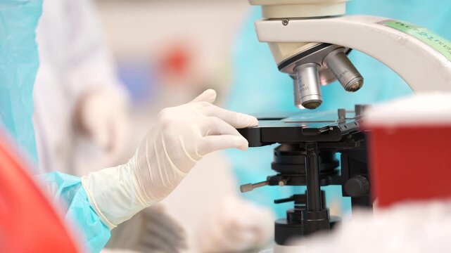 Laboratory microscope gloved hand medical research sample analysis sterile clinical scientific equipment focus adjustment lab microscope slide examination healthcare worker