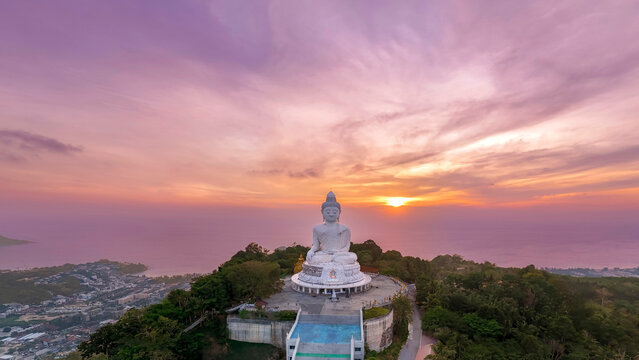 Aerial top panoramic sunset view great white marble Buddha statue sits serenely atop a lush Phuket peak top