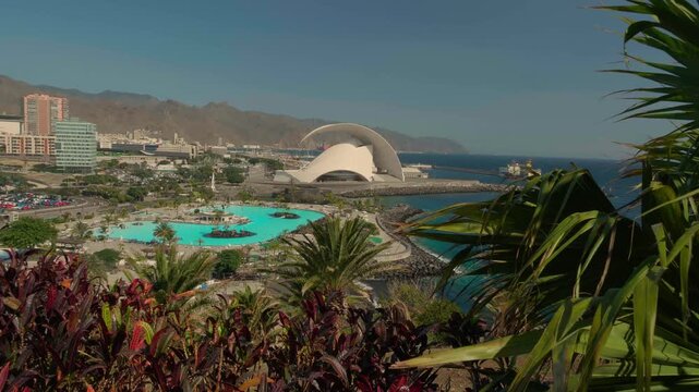 The Auditorio de Tenerife building seen from a park with tropical plants and pools in Santa Cruz de Tenerife. Wide shot.