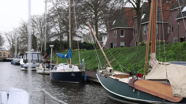 Rear facing boat view along the canal with moored boats, houses and station backdrop.