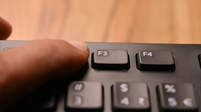 Man Pressing F2 Key on Keyboard to Rename File on Computer