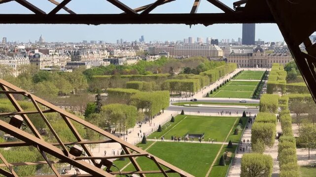 Elevated view of Champ de Mars park and Paris skyline, sunlit pathways and green lawns framed by trees, iconic monuments and city buildings under a clear blue sky