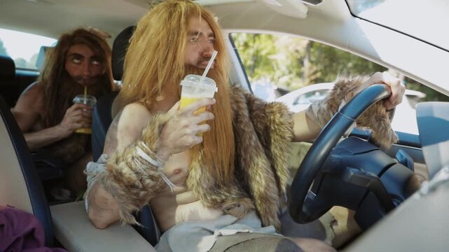 A group of modern cavemen are joyfully sitting in a car, happily enjoying their drinks together