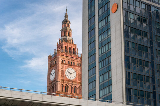 Brick clock tower beside modern glass building under blue sky