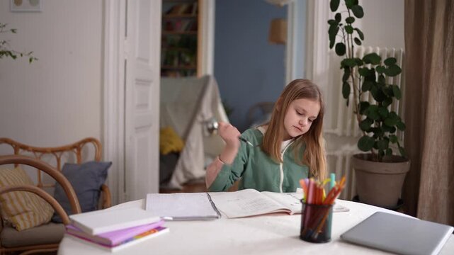 Young girl entering room sits at table, settles to study with notebook and colored pencils, cozy interior with plant and teepee in background, wicker chairs .