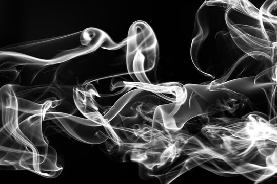 Abstract white smoke swirls isolated on black background.