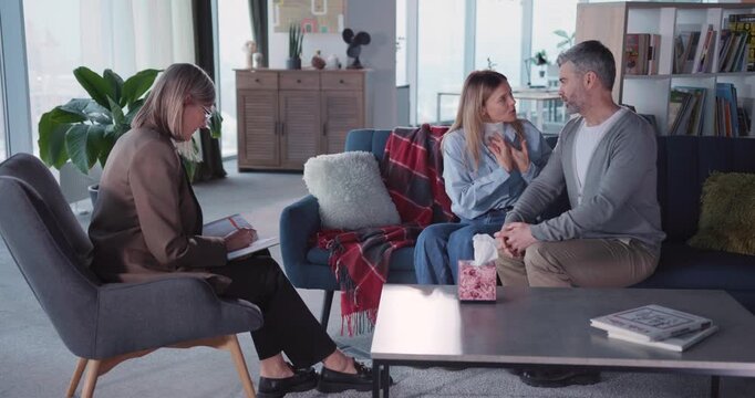 Family therapy session. married adult couple arguing making up conflict while talking to psychotherapist woman inside apartment.