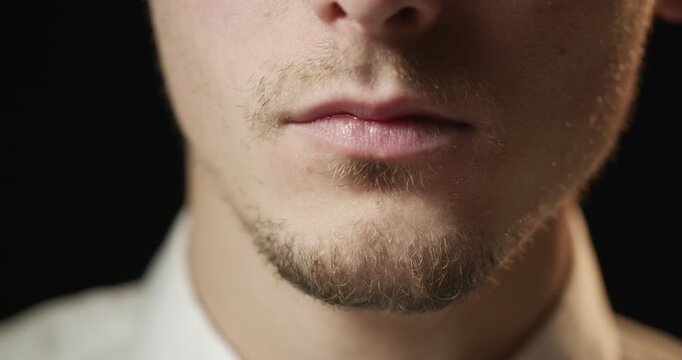 A close-up of a young man's hand bringing a glass of whiskey to his lips to take a sip.