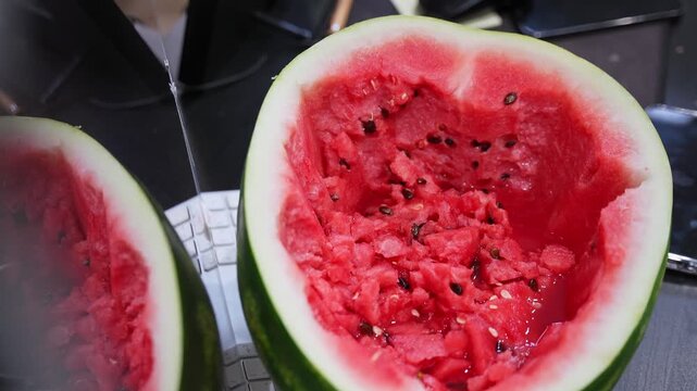 shot of a hollowed-out red watermelon resting on a white computer keyboard in a modern office. Capturing healthy snacking and summer food vibes within a workspace environment.