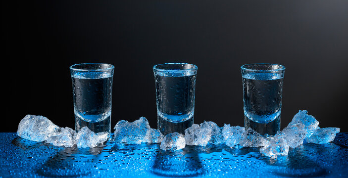 Vodka and crushed ice on a black table.