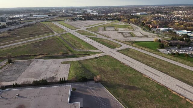 A counter-clockwise aerial drone orbit over the abandoned runways and decommissioned grounds of the former Buttonville Municipal Airport (CYKZ) in Markham, revealing the redevelopment site