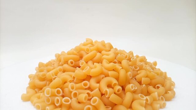 A Pile Of Elbow Macaroni Pasta Rotating on White Background, Uncooked Elbow Macaroni Pasta Ingredient