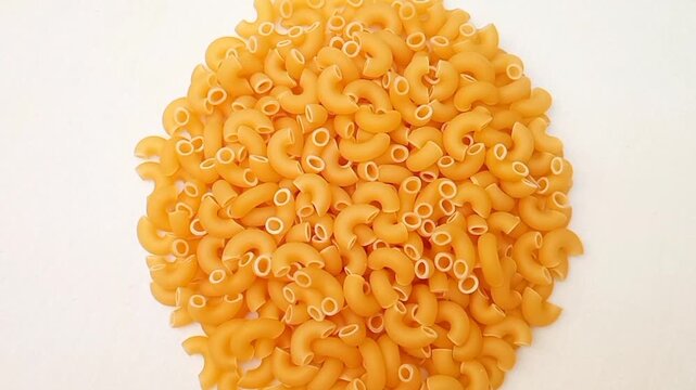 A Pile Of Elbow Macaroni Pasta Rotating on White Background, Uncooked Elbow Macaroni Pasta Ingredient