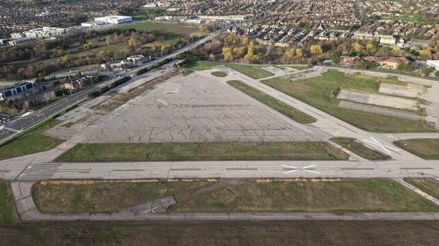 A cinematic drone shot flying straight rightward across the abandoned asphalt and weathered runways of the decommissioned Buttonville Municipal Airport (CYKZ) in Markham, Ontario
